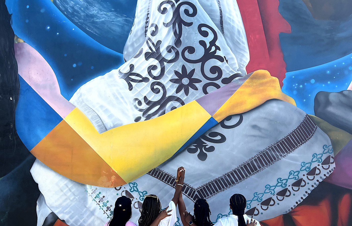 Travelers discovering West Africa — four women at a vibrant mural in Cotonou, Benin Republic